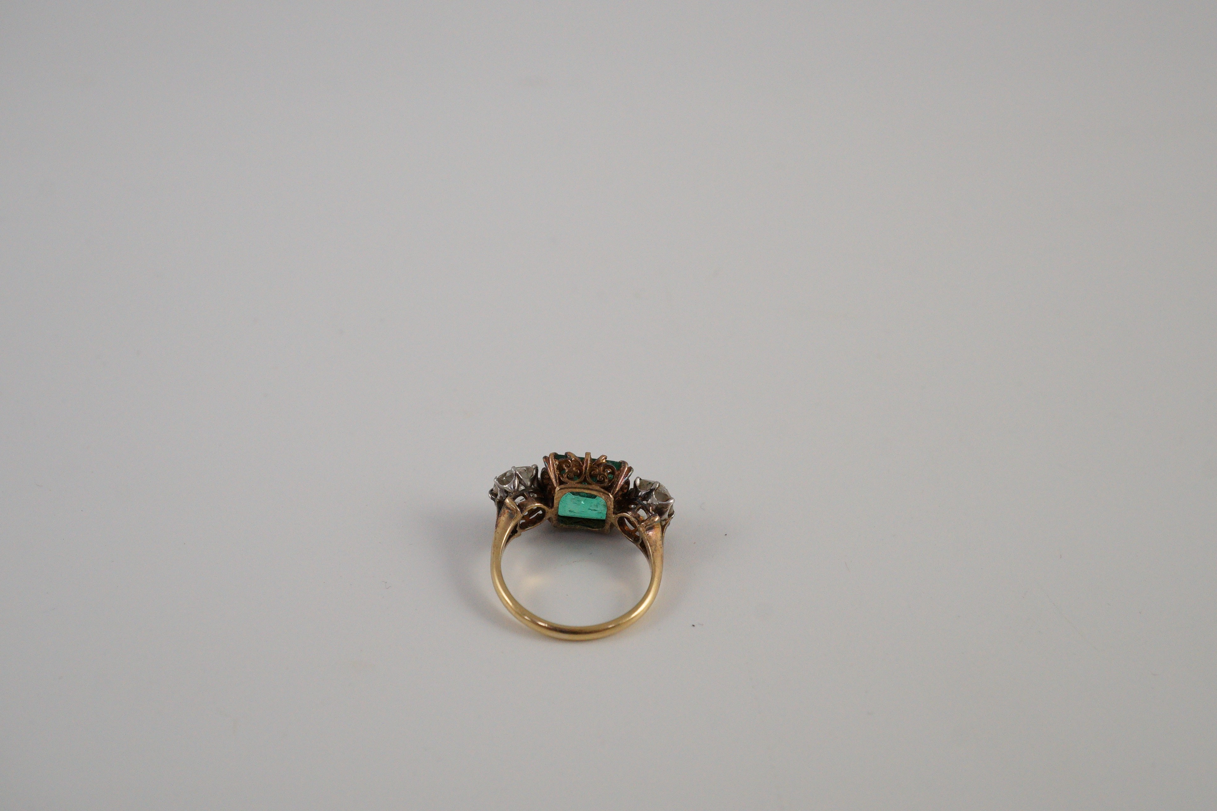 An early 20th century 18ct gold, square cut single stone emerald and two stone cushion cut diamond set dress ring